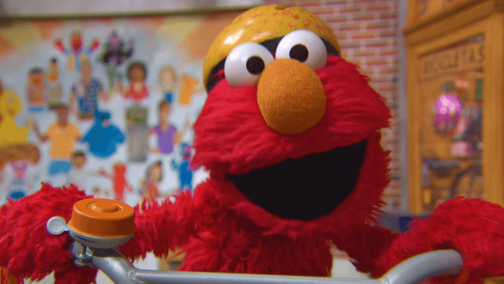 Tamir give Elmo his old bike to ride around.
